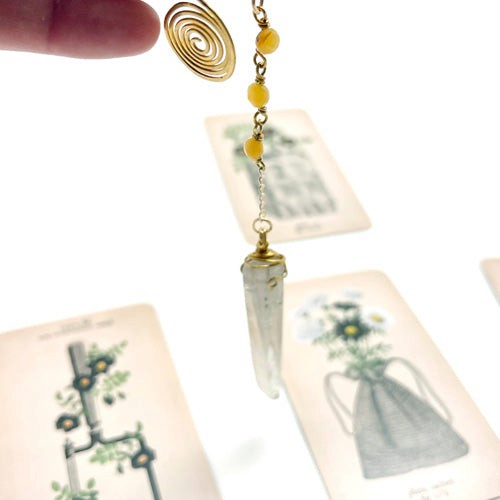 Ruby Feathers handcrafted crystal pendulum with brass spiral and yellow beads, used for dowsing and meditation.